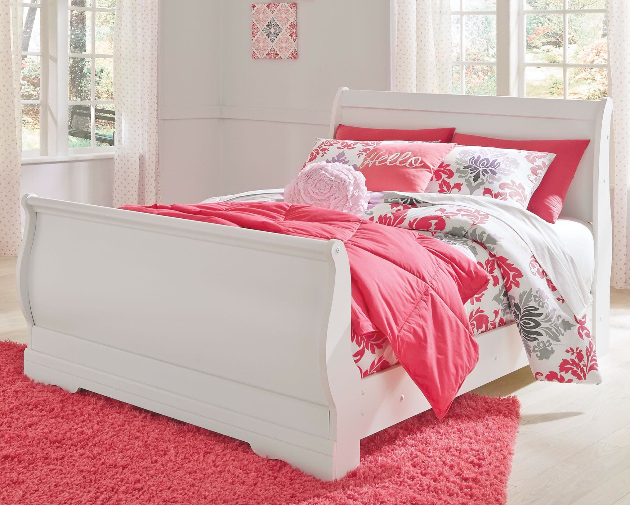 Cama tipo trineo blanca con edredón floral en la recámara de una niña